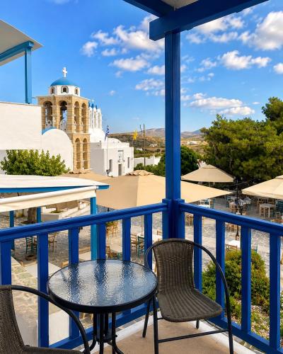 a table and chairs on a balcony with a clock tower at Cozy apartments Paros Kostos in Kóstos