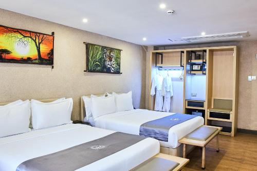 a hotel room with two beds and a tv at La Maison Royale South C in Nairobi