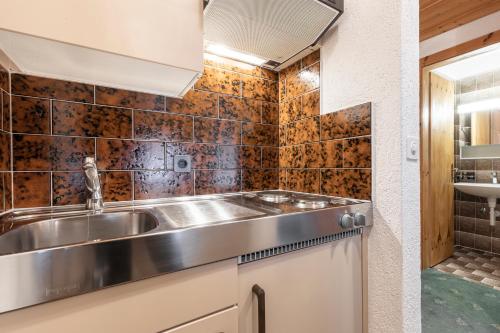 a kitchen with a stainless steel sink and tiles at Atlantis Apartments by MEIN SAMNAUN - MOUNTAIN HOMES in Samnaun