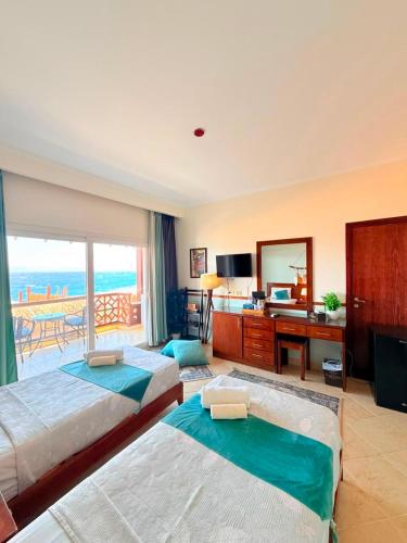 a hotel room with two beds and a desk with a view at Club Red Dahab Motel in Dahab
