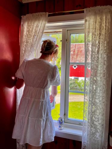 a woman in a white dress looking out of a window at Landlig leilighet in Landsem