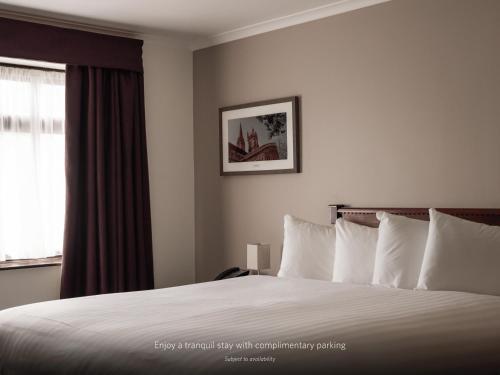 a bedroom with a bed with white pillows and a window at Copthorne Hotel Cardiff-Caerdydd in Cardiff