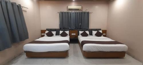two twin beds in a room with blue curtains at Hotel Purushottam in Dwarka