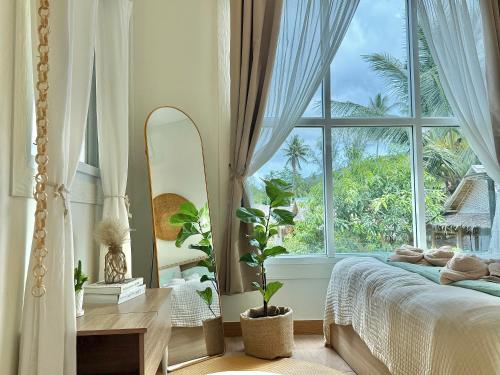 a bedroom with a bed and a large window at Chaloklum Beach House in Chaloklum