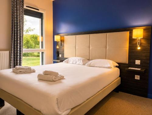 a bedroom with a large bed with towels on it at The Originals City, Hôtel La Verriaire, Cholet Sud in La Verrie