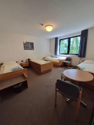 a room with two beds and a table and chairs at RTB-Hotel - Sportschule in Bergisch Gladbach