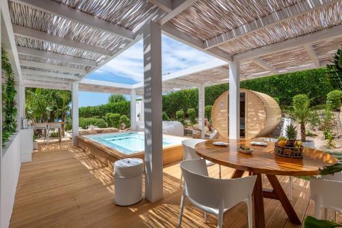 a patio with a table and a swimming pool at Dimitra Beach Hotel & Suites in Ágios Fokás
