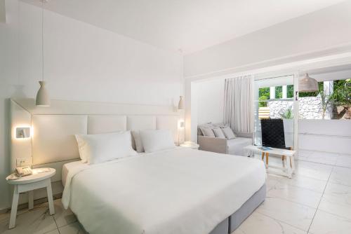a white bedroom with a large bed and a window at Dimitra Beach Hotel & Suites in Ágios Fokás