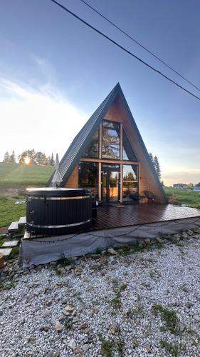 a house with a triangular roof on a wooden deck at La Știubei Cabin in Mărişel