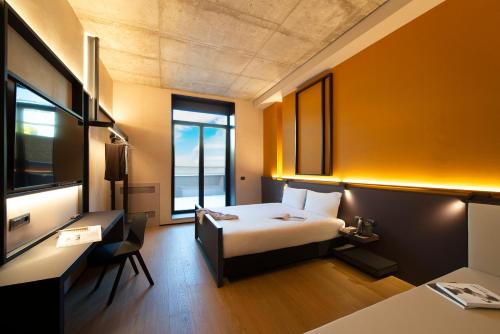 a hotel room with a bed and a desk and window at Breda Suites Hotel Milano in Milan