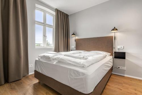a bedroom with a bed with white sheets and a window at Amtmann Residence by Heimaleiga in Selfoss