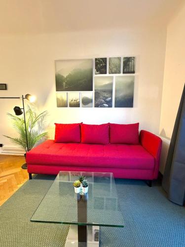 a red couch in a living room with a glass table at Stilvolles Apartment im Herzen von Krems in Krems an der Donau