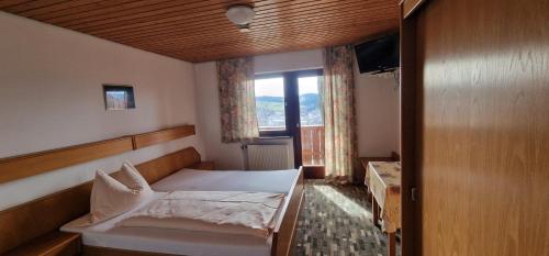 a small bedroom with a bed and a window at Berggasthof Hinhart in Regen