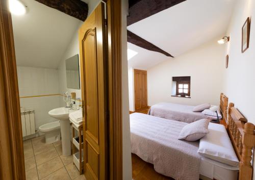 a bathroom with two beds and a sink in a room at La Posada Nueva in Viscarret-Guerendiáin