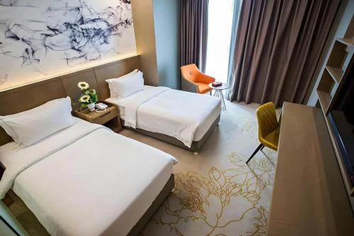 a hotel room with two beds and a desk at Grand Flora Hotel in Malacca