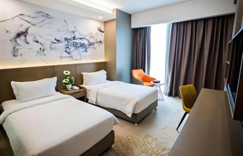 a hotel room with two beds and a tv at Grand Flora Hotel in Malacca