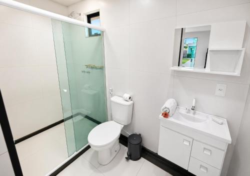 a bathroom with a toilet and a glass shower at Pousada Oásis Tropical in Porto De Galinhas