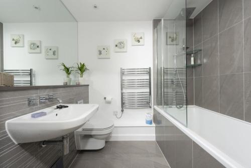 a bathroom with a sink and a toilet and a bath tub at The Penthouse Fistral Beach, Newquay in Crantock