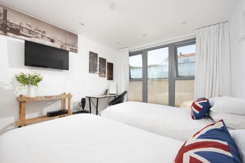 two beds in a room with a tv and a window at The Penthouse Fistral Beach, Newquay in Crantock