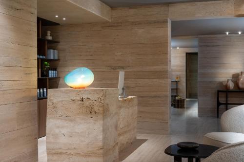 a lobby with a stone wall with a blue orb on top at The YACHT - By Fattal Limited Edition in Herzliya B