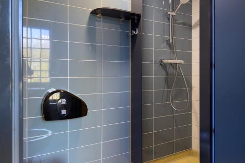 a bathroom with a shower with blue tiles at Stayokay Hostel Heemskerk - fully renovated April 2026 in Heemskerk
