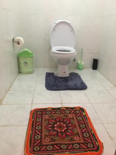 a bathroom with a toilet and a rug on the floor at Hotel Khangri in Namche