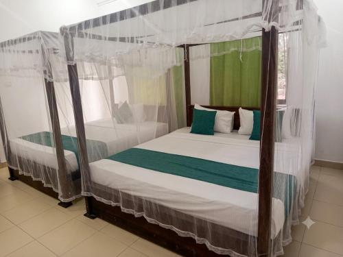a bedroom with a canopy bed with white and green pillows at Lavish Resort Sigiriya in Inamaluwa