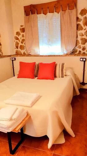 a white bed with red pillows and a window at Casa Rural La Changa in Losar de la Vera