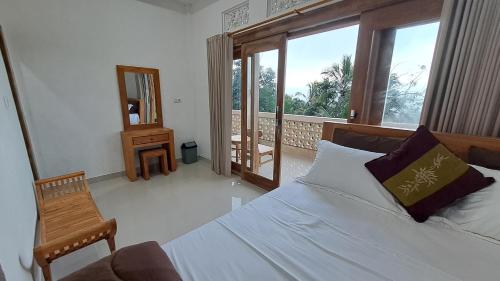 a bedroom with a bed and a chair and a window at Double view point sibetan in Tenganan