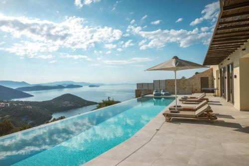 a swimming pool with lounge chairs and an umbrella at Villa Symposium Infinity in Sivota