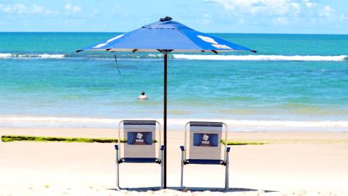 two chairs under an umbrella on the beach at Transamerica Dunas de Marapé - Alagoas in Jequia da Praia