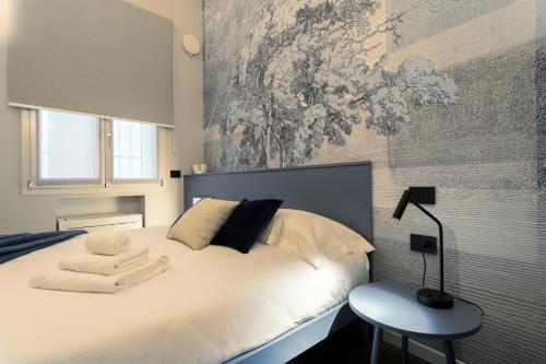 a bedroom with a white bed with a lamp and a table at GuestHost - Vivaldi Inverno Apartment in Treviglio