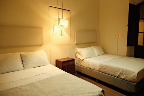 a hotel room with two beds and a lamp at Hotel Pata y Perro in Tarija
