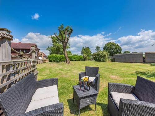 a patio with two chairs and a table on a lawn at The Pod At Egmont in Newenden