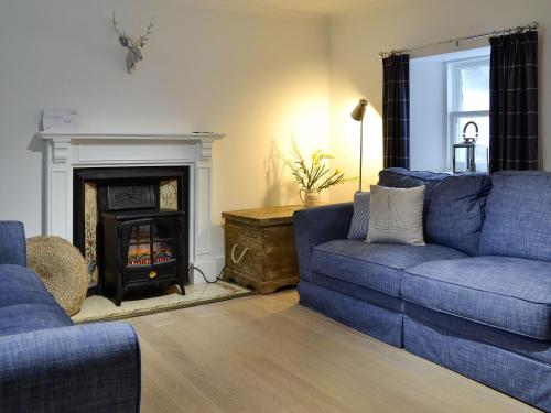 ein Wohnzimmer mit einem blauen Sofa und einem Kamin in der Unterkunft Jebel in Cullen