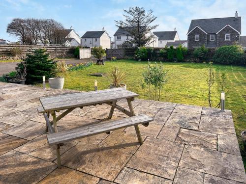 a wooden bench sitting on top of a stone patio at The Barn in Helston