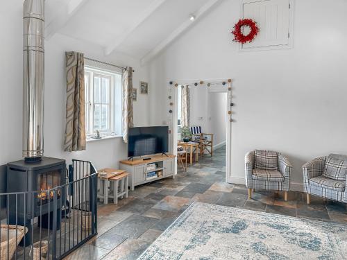 a living room with a fireplace and a tv at The Barn in Helston