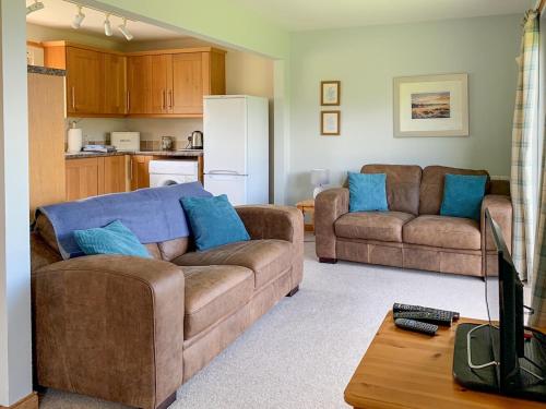 a living room with two couches and a kitchen at Thistle Cottage - Uk5867 in Achmelvich