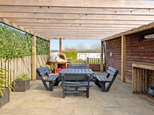 a patio with a table and benches and a grill at Egmont Farmhouse in Newenden
