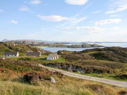 a house on a hill next to the ocean at Orchid Cottage - Uk5866 in Achmelvich