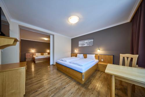 a bedroom with a bed and a table in it at Hotel Bärenbachhof in Saalbach-Hinterglemm