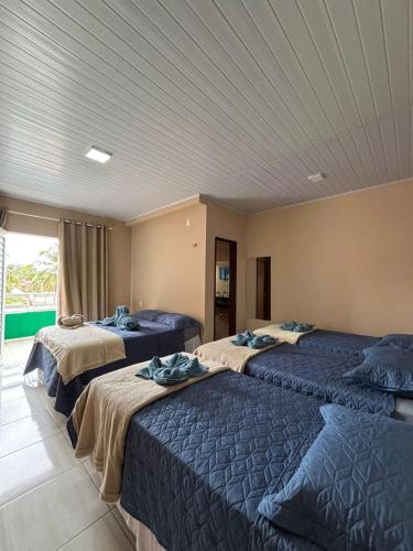 a room with three beds with blue blankets at Pousada Residência Lençóis in Barreirinhas