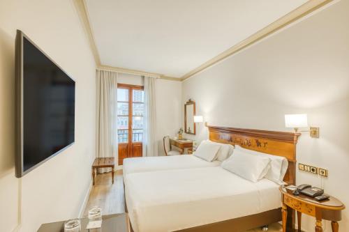 a hotel room with a bed and a flat screen tv at Sercotel Arenal Bilbao in Bilbao