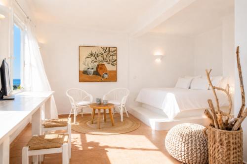 a white bedroom with a bed and a table and chairs at Yakinthos Suites in Mykonos