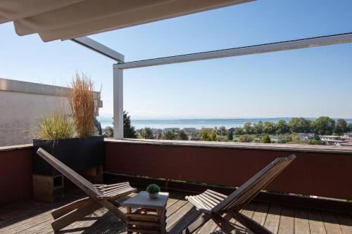two chairs and a table on a balcony with a view at Apartment Lichterfunkeln für junge Paare mit Panorama-Seeblick in Daisendorf