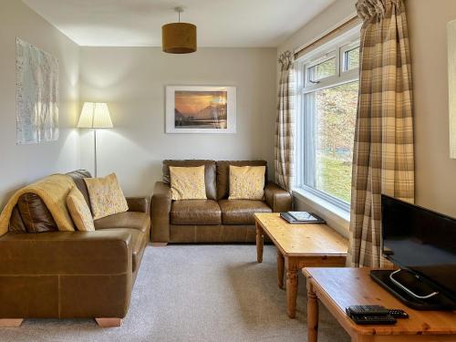 a living room with a couch and a tv at Fern Cottage - Uk5868 in Achmelvich