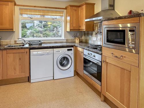 a kitchen with a washer and dryer and a window at Fern Cottage - Uk5868 in Achmelvich