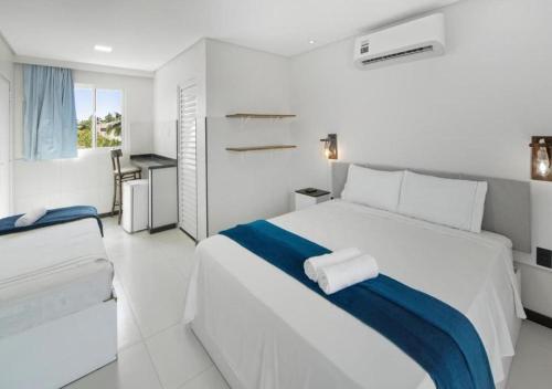 a white bedroom with a large bed with blue and white sheets at Pousada Oásis Tropical in Porto De Galinhas