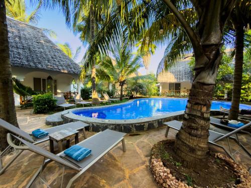 a resort pool with lounge chairs and a palm tree at African Bungalows in Nungwi
