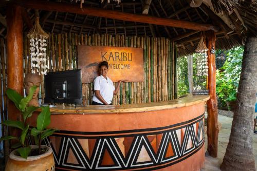 a woman standing at a bar in a restaurant at African Bungalows in Nungwi